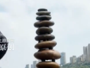 女生在江边搭石头塔垒到三十三层